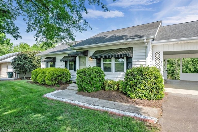 view of front facade featuring roof with shingles, a front lawn, and driveway