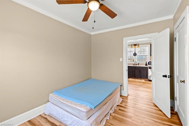 bedroom with light wood-type flooring, crown molding, and baseboards