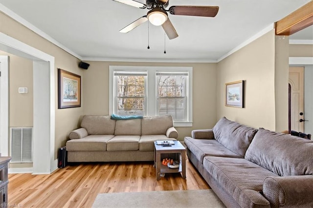 living room featuring a ceiling fan, light wood-type flooring, visible vents, and crown molding