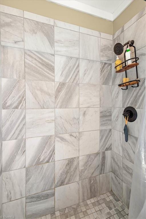 bathroom with a tile shower and crown molding