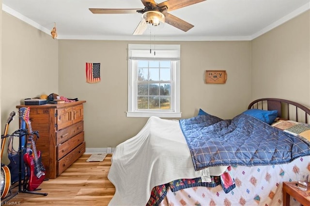 bedroom featuring ornamental molding, light wood-style floors, baseboards, and a ceiling fan