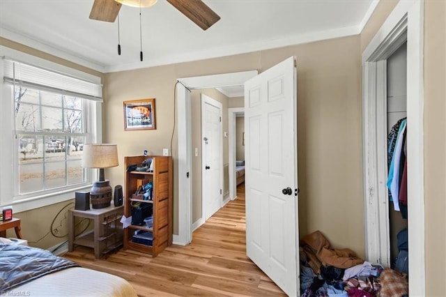 bedroom featuring ornamental molding, light wood-style flooring, baseboards, and a ceiling fan