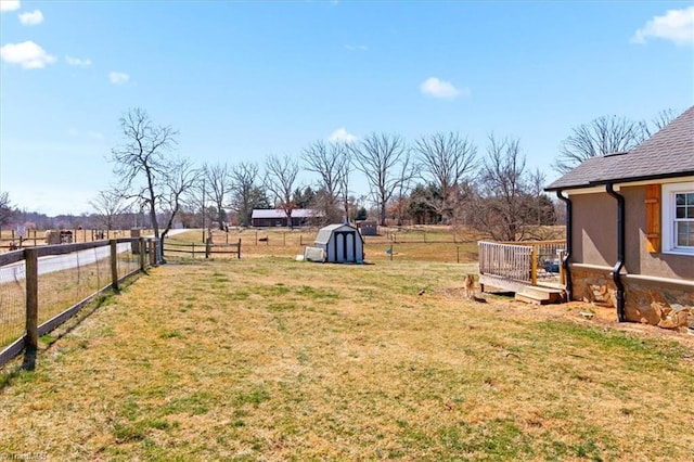 view of yard featuring a storage shed, a fenced backyard, a deck, and an outdoor structure