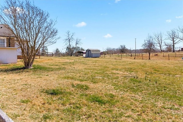 view of yard with an outbuilding, a rural view, fence, and a storage unit