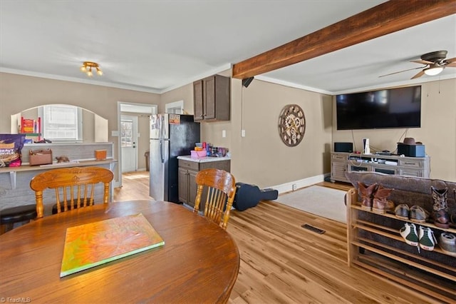 dining space with beam ceiling, ornamental molding, ceiling fan, light wood-type flooring, and baseboards