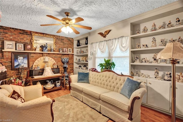 living room featuring a textured ceiling, light wood-type flooring, ceiling fan, and ornamental molding