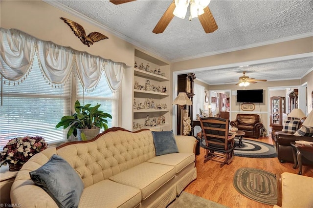 living room featuring ornamental molding, a textured ceiling, ceiling fan, built in features, and hardwood / wood-style floors