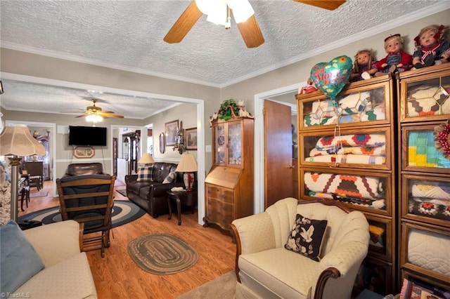 living room featuring ceiling fan, hardwood / wood-style floors, a textured ceiling, and ornamental molding