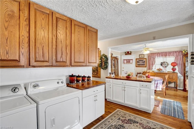 laundry room featuring washing machine and clothes dryer, ceiling fan, cabinets, and a textured ceiling