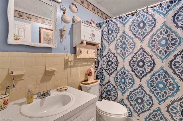 bathroom with a shower with curtain, a textured ceiling, toilet, vanity, and tile walls