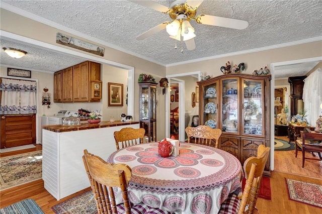 dining room with a textured ceiling, light wood-type flooring, ceiling fan, and ornamental molding