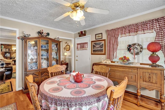 dining space with a textured ceiling, light hardwood / wood-style floors, ceiling fan, and crown molding