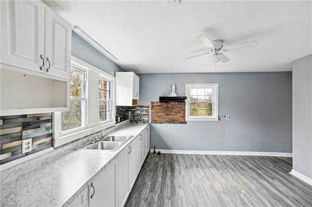 kitchen with backsplash, white cabinetry, sink, and hardwood / wood-style flooring