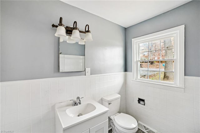 bathroom with vanity, toilet, and tile walls