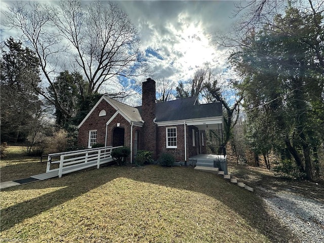 view of front facade featuring a chimney, a front lawn, and brick siding