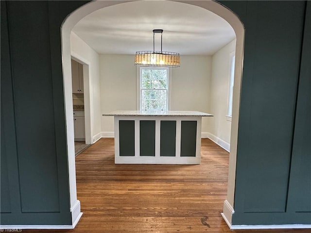 interior space with baseboards, arched walkways, and dark wood finished floors