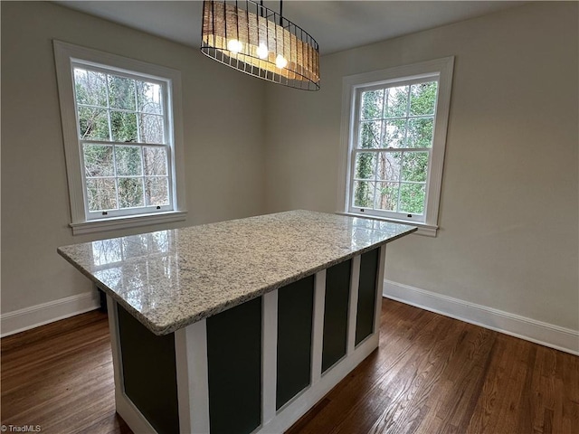 kitchen with dark wood-style floors, light stone countertops, and baseboards