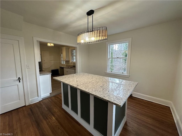 kitchen featuring baseboards, dark wood-style flooring, a center island, hanging light fixtures, and light stone countertops