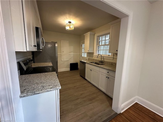 kitchen with baseboards, white cabinets, dark wood-style flooring, stainless steel appliances, and a sink