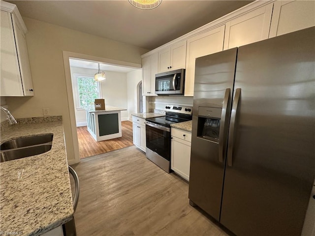 kitchen featuring appliances with stainless steel finishes, light wood-type flooring, a sink, and white cabinetry