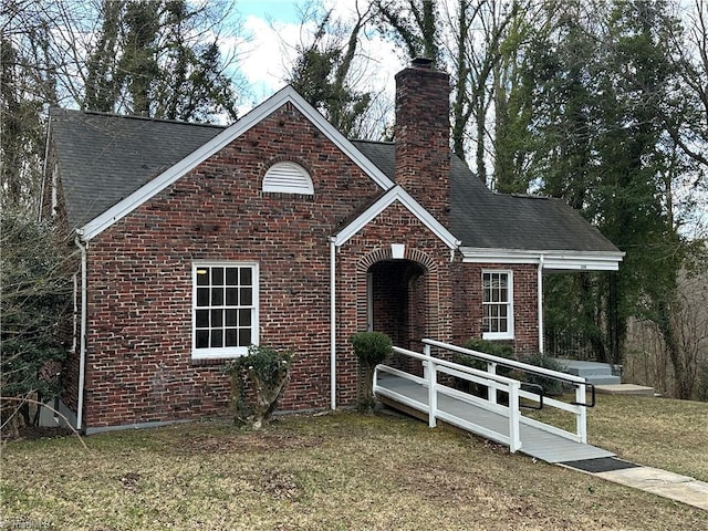 view of front of home featuring a shingled roof, a chimney, a front lawn, and brick siding