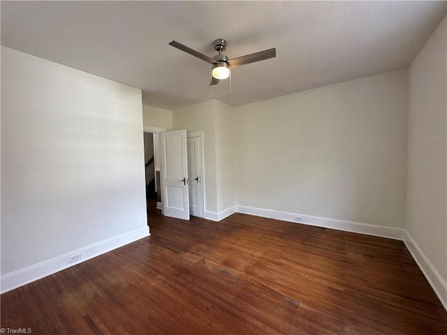 empty room with ceiling fan, dark wood finished floors, and baseboards