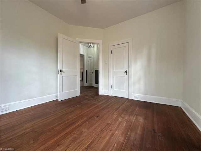 spare room with baseboards and wood finished floors