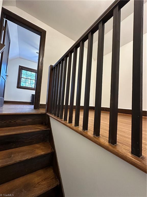 stairs with vaulted ceiling and wood finished floors