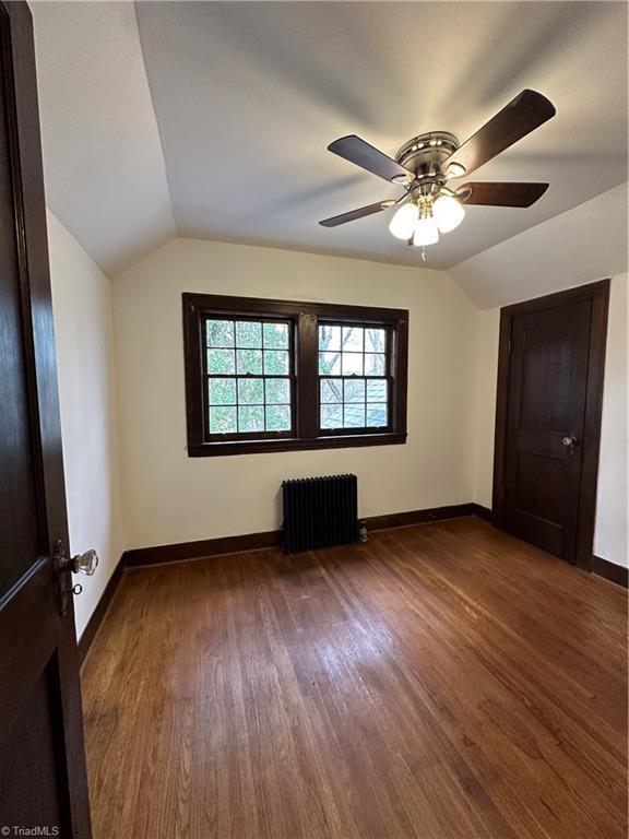 bonus room featuring vaulted ceiling, dark wood-style flooring, and radiator