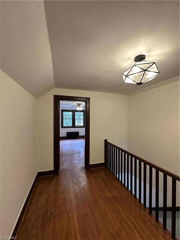 hall featuring lofted ceiling, wood finished floors, and baseboards