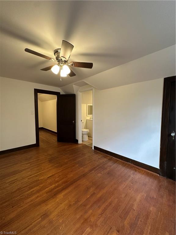 spare room with vaulted ceiling, ceiling fan, wood finished floors, and baseboards