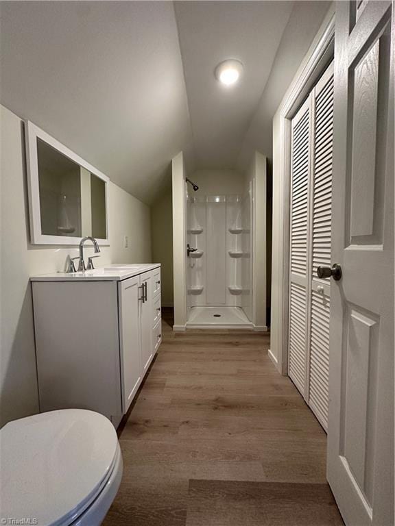 full bath featuring lofted ceiling, wood finished floors, a shower stall, and vanity