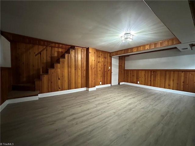 interior space featuring wood walls, baseboards, stairway, and wood finished floors