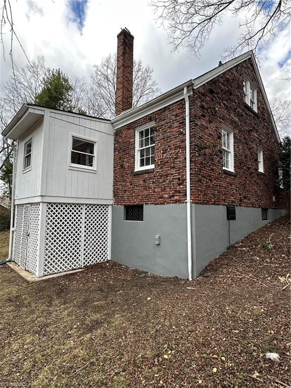 rear view of house with a chimney and brick siding