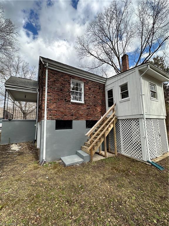 rear view of house featuring a chimney, a carport, and brick siding