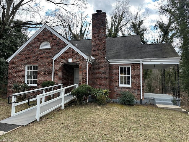 view of front of home featuring brick siding, a chimney, a shingled roof, a porch, and a front lawn