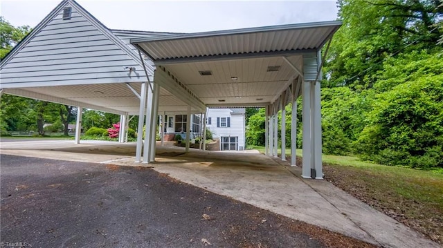 view of parking with driveway and a detached carport