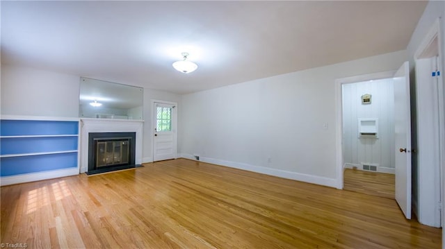 unfurnished living room with light wood-type flooring, a glass covered fireplace, and baseboards
