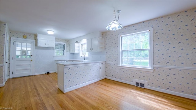 kitchen featuring wallpapered walls, light wood-style flooring, a peninsula, white cabinets, and open shelves