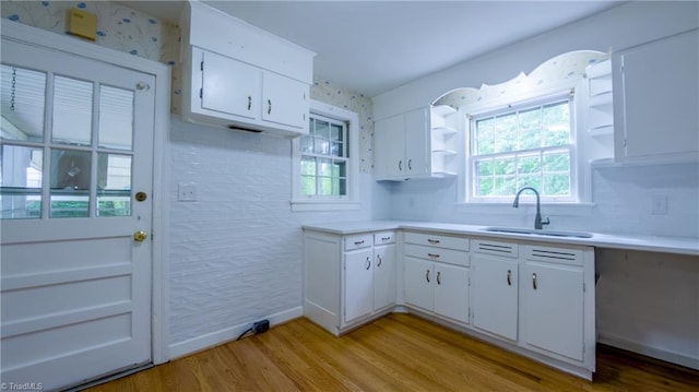 kitchen featuring a sink, light countertops, light wood finished floors, and white cabinets
