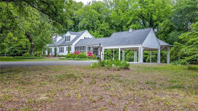 view of front of home featuring a carport, a front yard, and a chimney