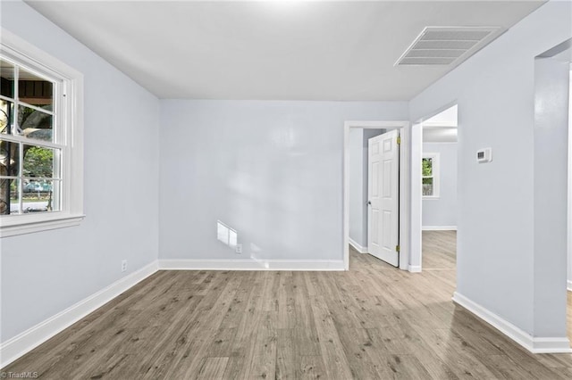 spare room with plenty of natural light, wood finished floors, and visible vents