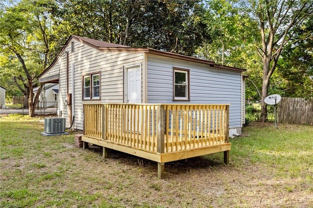 back of house with central AC, a wooden deck, and a lawn