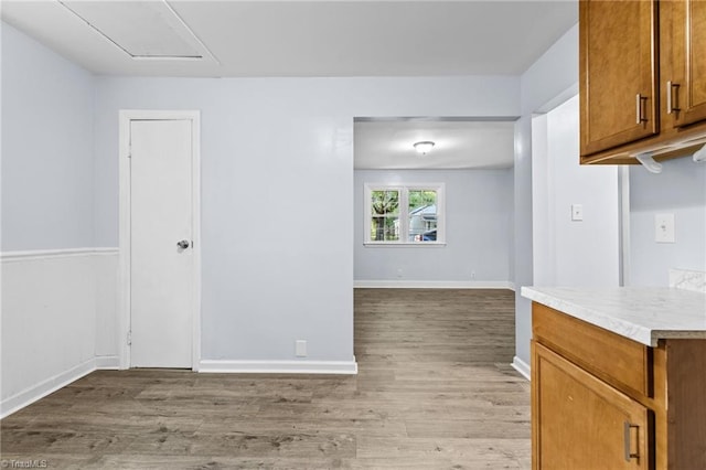 kitchen featuring light countertops, light wood-style flooring, baseboards, and brown cabinets