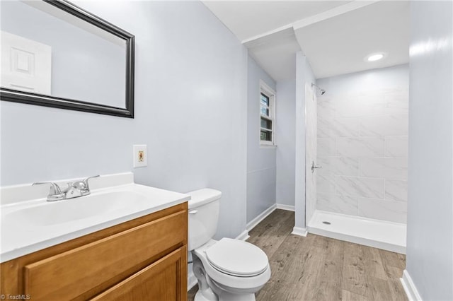 bathroom with vanity, toilet, a tile shower, and hardwood / wood-style floors