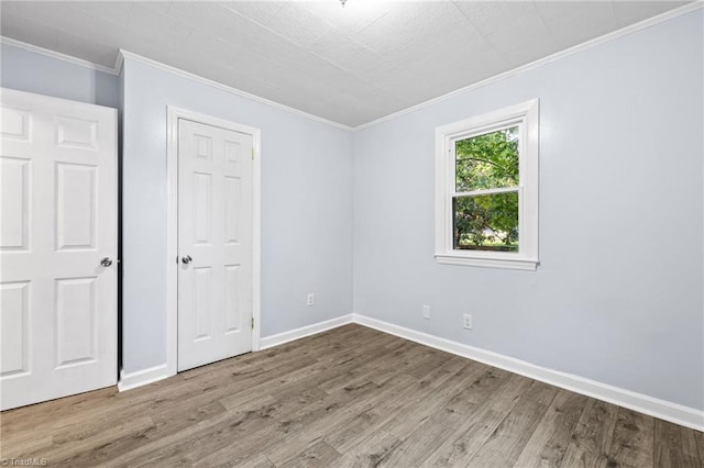 unfurnished bedroom with ornamental molding, baseboards, and wood finished floors