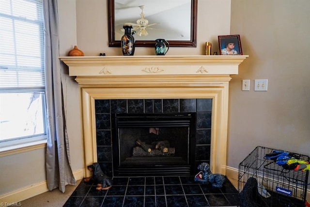 interior details featuring ceiling fan and a tile fireplace