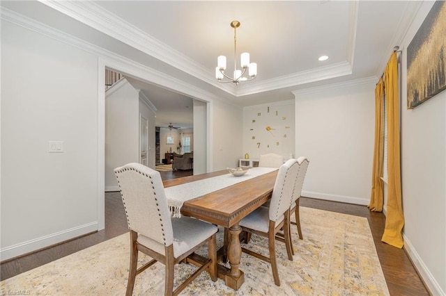 dining area featuring hardwood / wood-style flooring, crown molding, a raised ceiling, and a chandelier