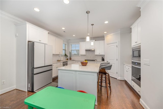 kitchen with white cabinetry, crown molding, a kitchen island, pendant lighting, and stainless steel appliances