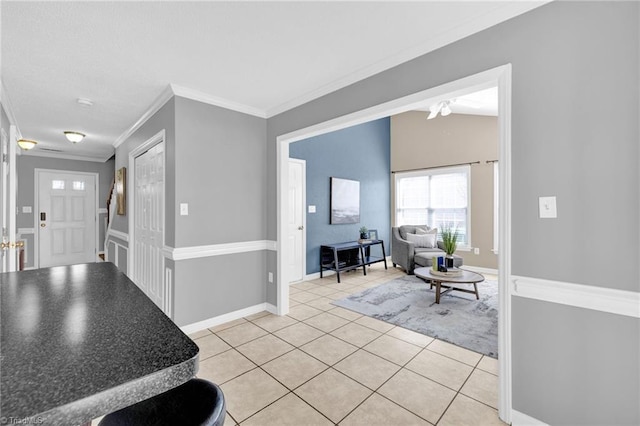 foyer entrance with light tile patterned flooring, vaulted ceiling, baseboards, and ornamental molding